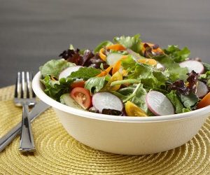 Open cardboard bowl with food inside with a knife and fork on the side